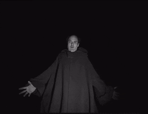 a black and white photo of a man in a robe with a hood