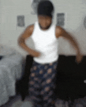 a man in a white tank top and pajama pants is dancing .