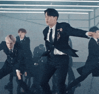 a group of men in suits and ties are dancing together on a stage .