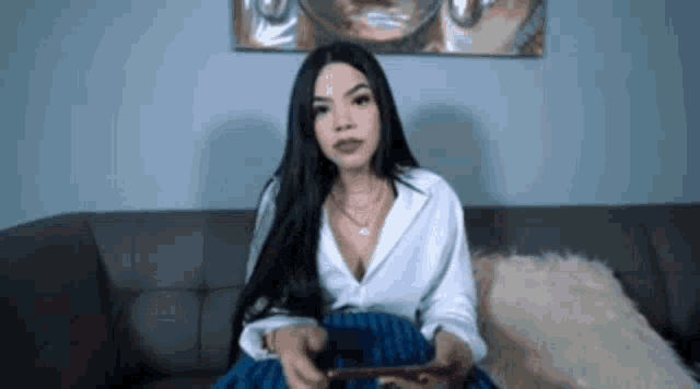 a woman is sitting on a couch holding a nintendo switch .