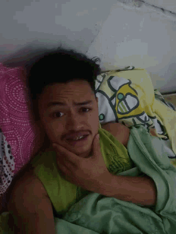 a man laying in bed with a hello kitty blanket