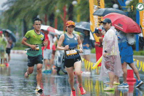 a group of runners are running in the rain and one of them has the number 251 on her shirt