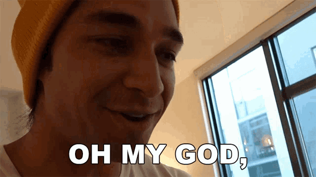 a man in a yellow hat says oh my god in front of a window
