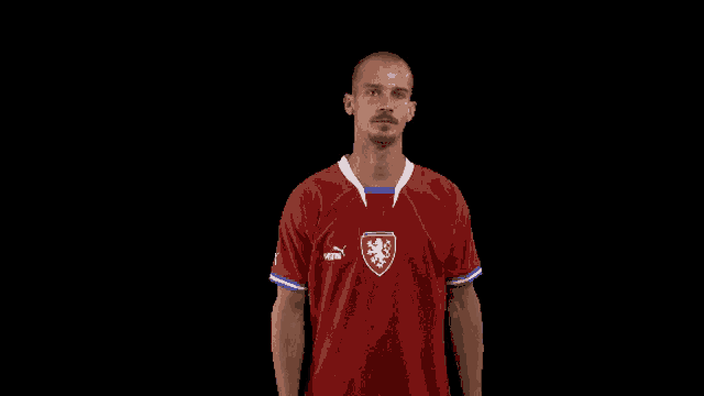 a man is wearing a red puma jersey with a lion on it