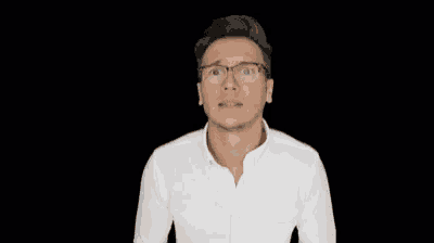 a man wearing glasses and a white shirt is making a face .