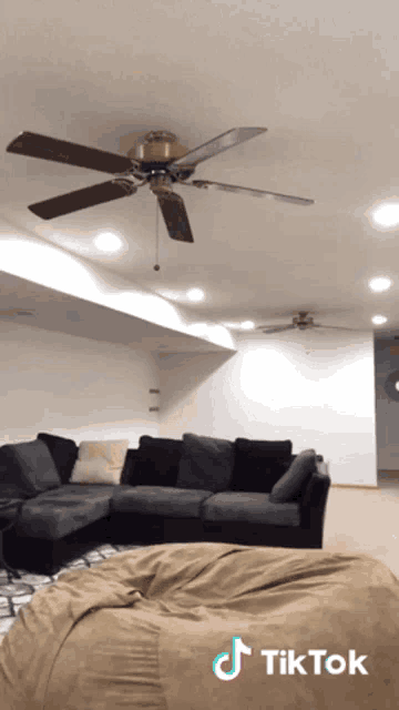 a living room with a couch and a ceiling fan and a tiktok logo