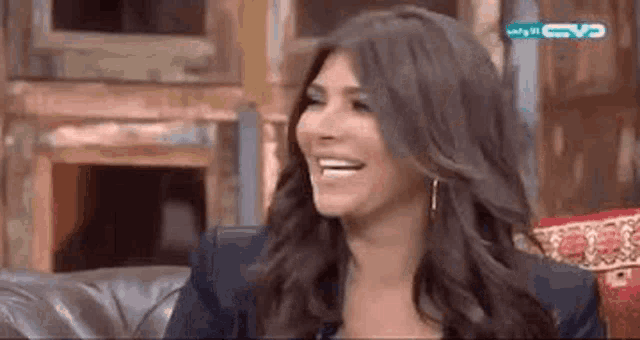 a woman is smiling while sitting on a couch on a television show .