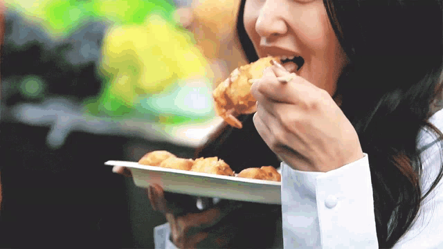 a woman in a white shirt is eating food from a white plate