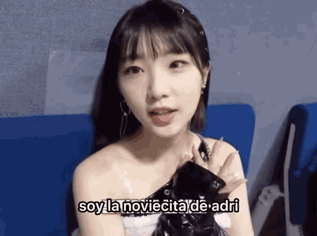 a woman is sitting on a blue couch with the words soy la noviacita de adri written below her