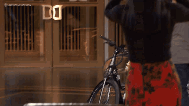 a woman is riding a bike in front of a building with a sign that says dc .