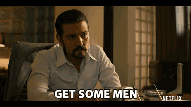 a man is sitting at a desk with the words get some men on the screen