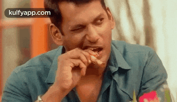 a man is sitting at a table eating a piece of food .
