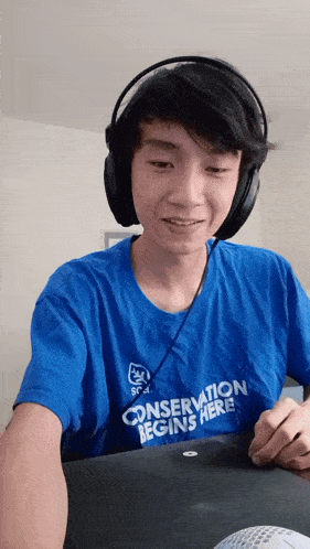 a young man wearing headphones and a shirt that says conservation begins here