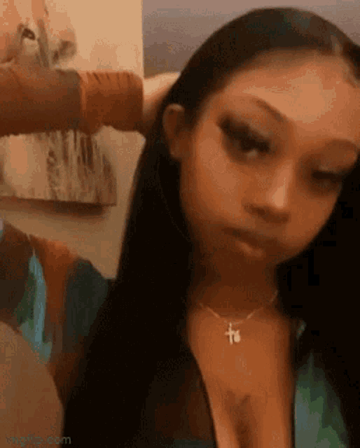 a woman with long black hair is holding her hair in a ponytail .