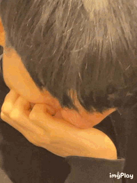 a close up of a person covering their mouth with their hand