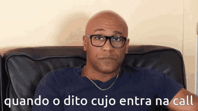 a bald man wearing glasses is sitting on a couch with the words " quando o dito cujo entra na call " below him