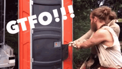 a man is standing in front of a red portable toilet that says gtfo