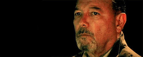 a close up of a man 's face with a beard and a hat .