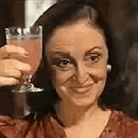 a woman is holding a glass of pink liquid in her hand .