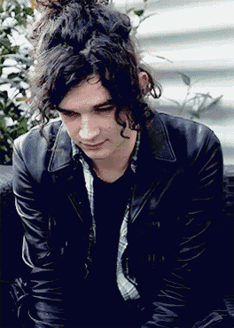 a young man with long curly hair wearing a black leather jacket