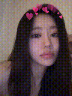 a woman with long black hair and pink hearts on her head is taking a selfie .
