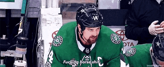 a hockey player wearing a green jersey and a black helmet is sitting in the stands .