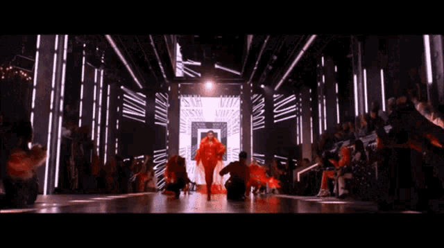 a man in a red dress is walking down a runway