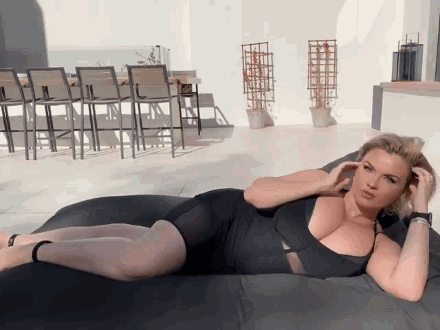 a woman in a black dress laying on a bed