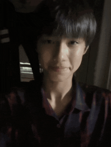 a young man wearing a plaid shirt is making a peace sign