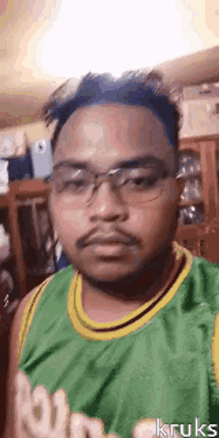 a man with a beard and glasses is wearing a green and yellow jersey .