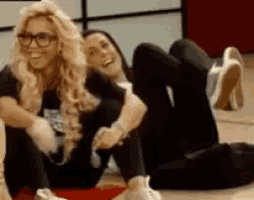 two women are laying on the floor with their legs crossed and smiling .