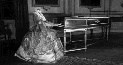 a woman in a long dress is playing a piano in a room .