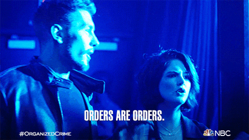 a man and a woman are standing in a dark room with the words orders are orders