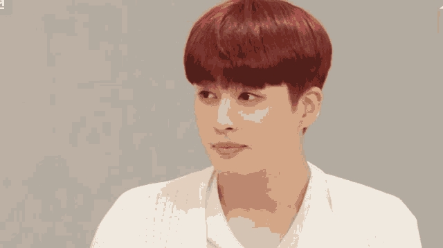 a man with red hair and a white shirt looks at the camera