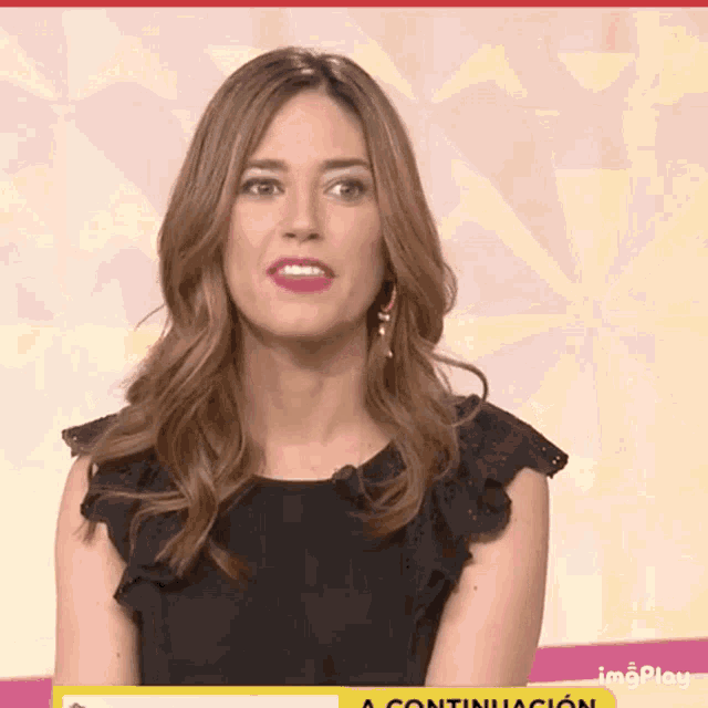 a woman is sitting in front of a yellow sign that says continuacion