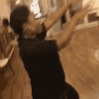 a woman is dancing in a room with her arms outstretched .