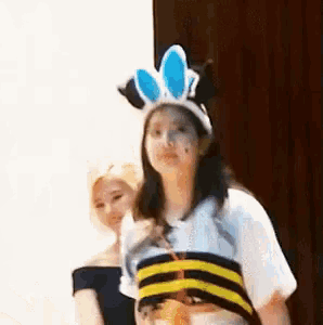 a woman wearing a bee costume and bunny ears is standing next to another woman wearing a bee costume .