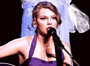 a woman in a purple dress singing into a microphone on stage