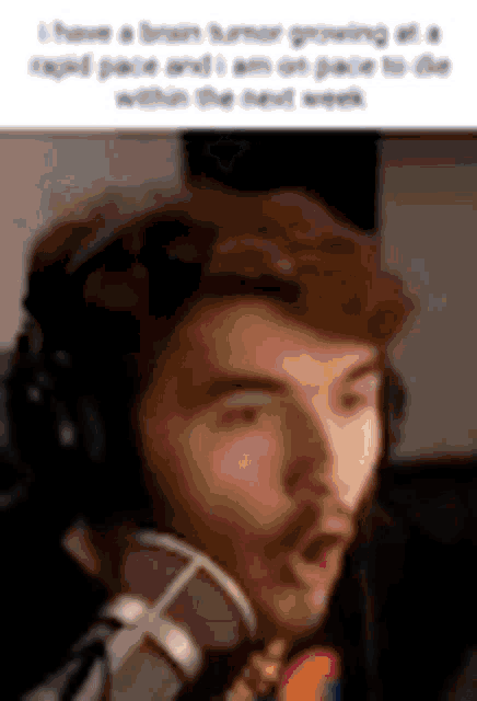 a man wearing headphones is talking into a microphone and making a funny face .