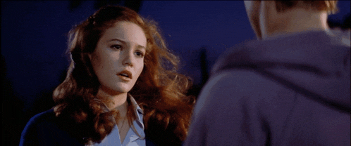 a woman with red hair is looking at a man in a purple shirt