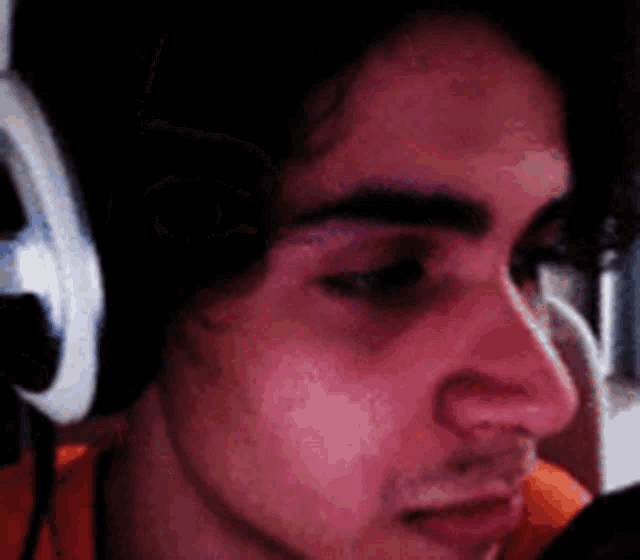 a close up of a man wearing headphones looking at a microphone .