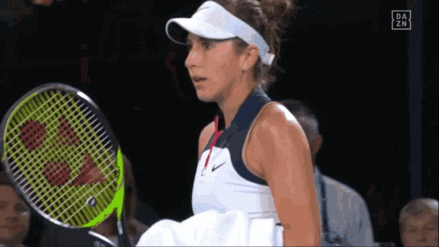 a woman holding a tennis racquet in front of a screen that says da zn