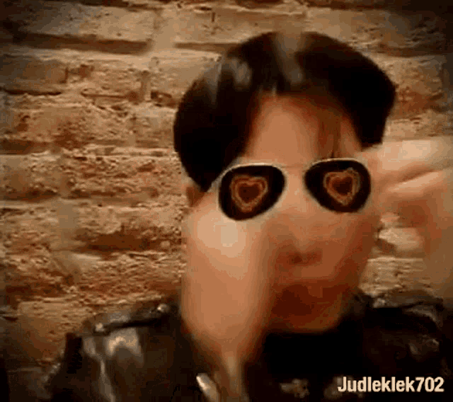 a man wearing sunglasses with hearts on them is smoking a cigarette .