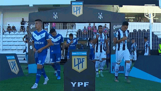 a group of soccer players are walking in front of a ypf sign