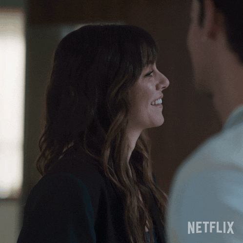 a woman is smiling and looking at a man with a netflix logo in the corner
