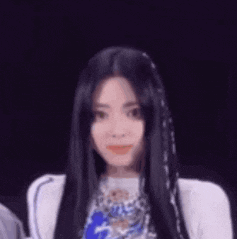 a close up of a woman with long black hair wearing a white shirt .