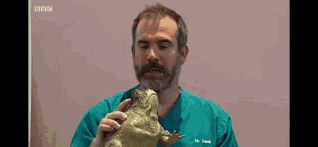 a man with a beard is wearing a green scrub top that says dr. leed