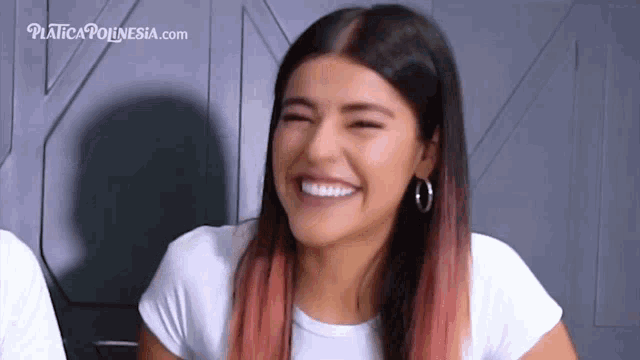 a woman in a white shirt is laughing with a website in the background
