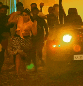 a group of people are dancing in front of a car with ka 222 on the back