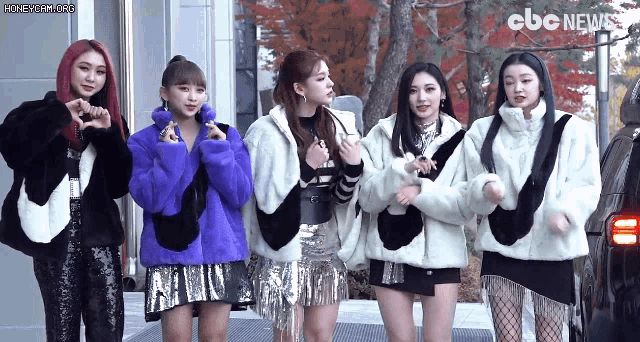 a group of girls are standing next to each other wearing fur coats